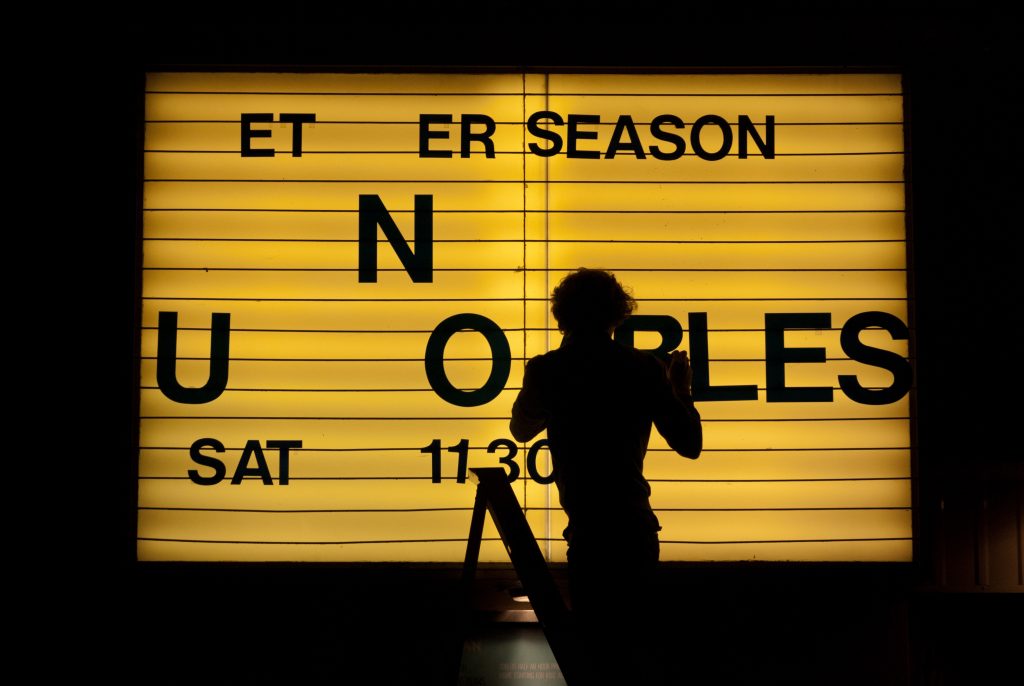 A picture of a person changing the lettering on a cinema sign
