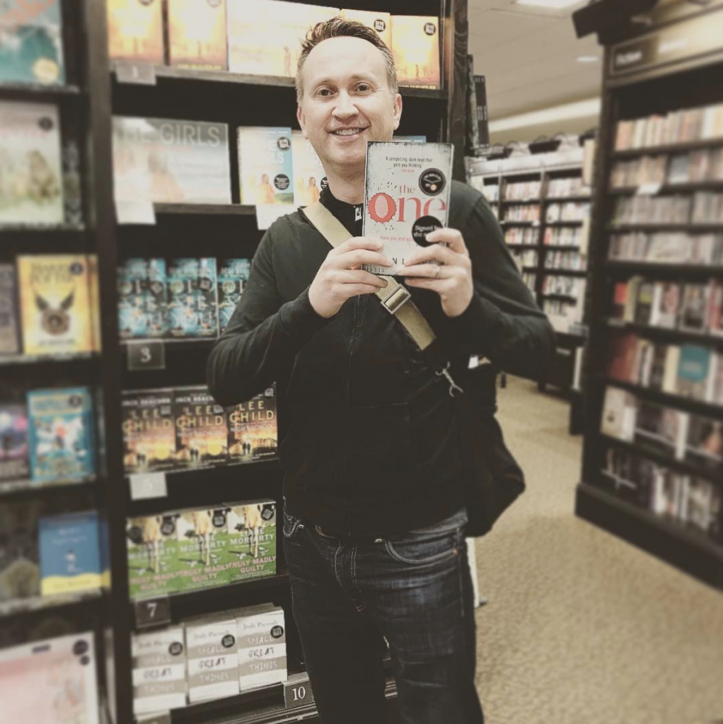 A picture of John holding his book