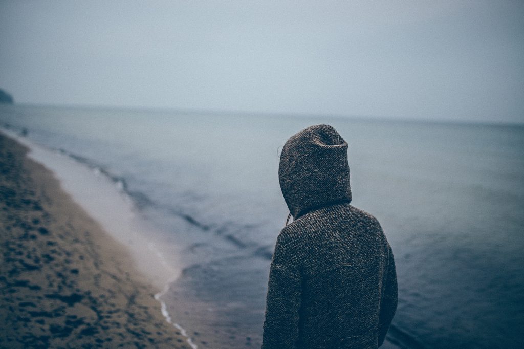A picture of a depressed looking person on a dark beach